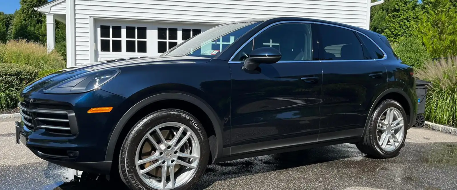 Dark blue Porsche Cayenne after a mobile detail in a Long Island driveway