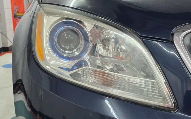 Clear, restored headlight on a dark blue Buick after headlight restoration