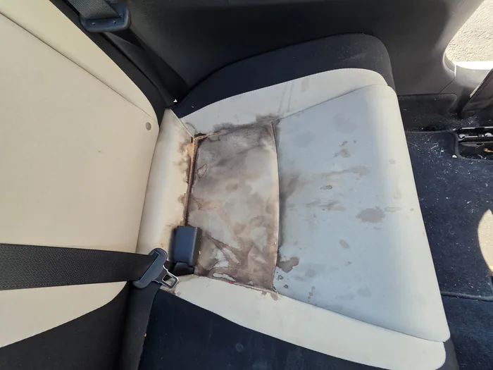 Stained light cloth rear car seat before an interior detail