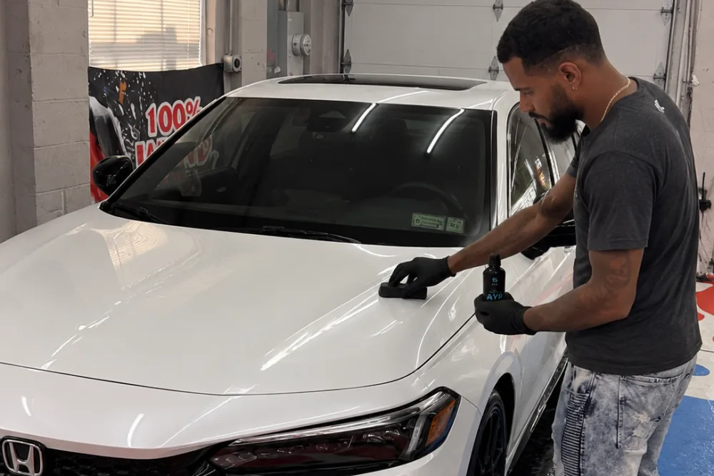 Technician hand applying ceramic coating to a white Honda Civic at our Islip Terrace shop