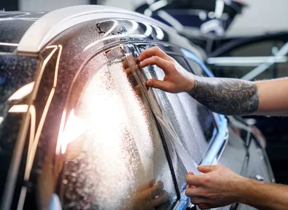 Installer applying ceramic tint film to a car side window