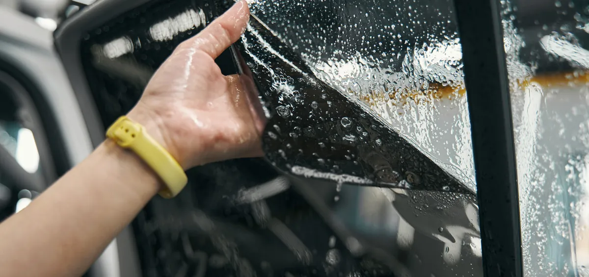 Installer peeling the backing off window tint film on a wet side window